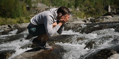 Person splashing water on their face in a river.