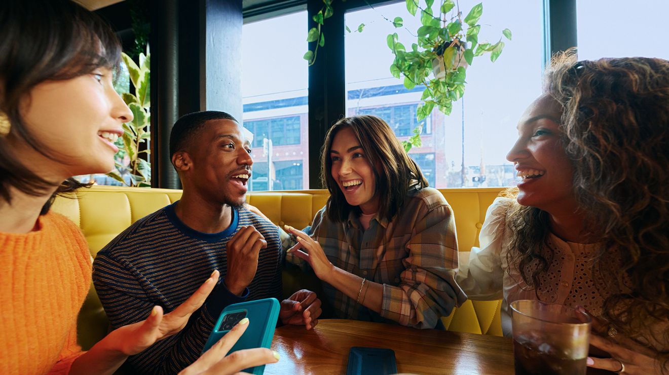 Four friends laughing in a diner booth