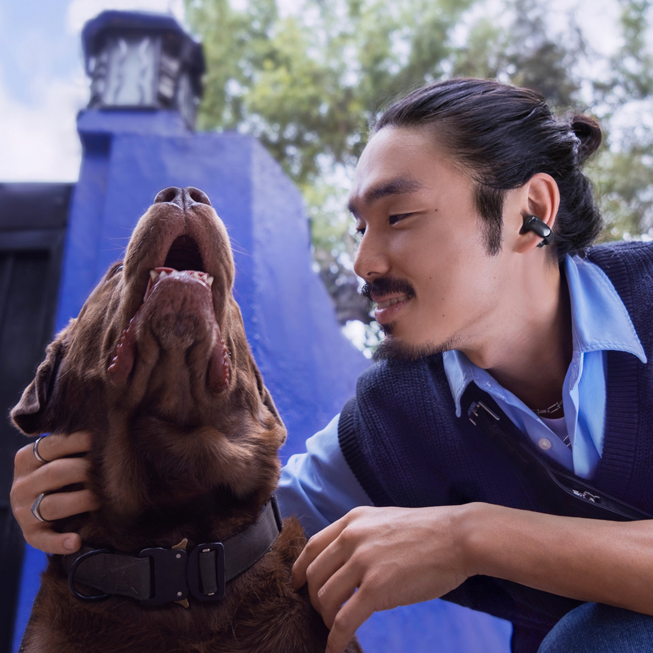 Man with his dog wearing Bose Ultra Open Earbuds.