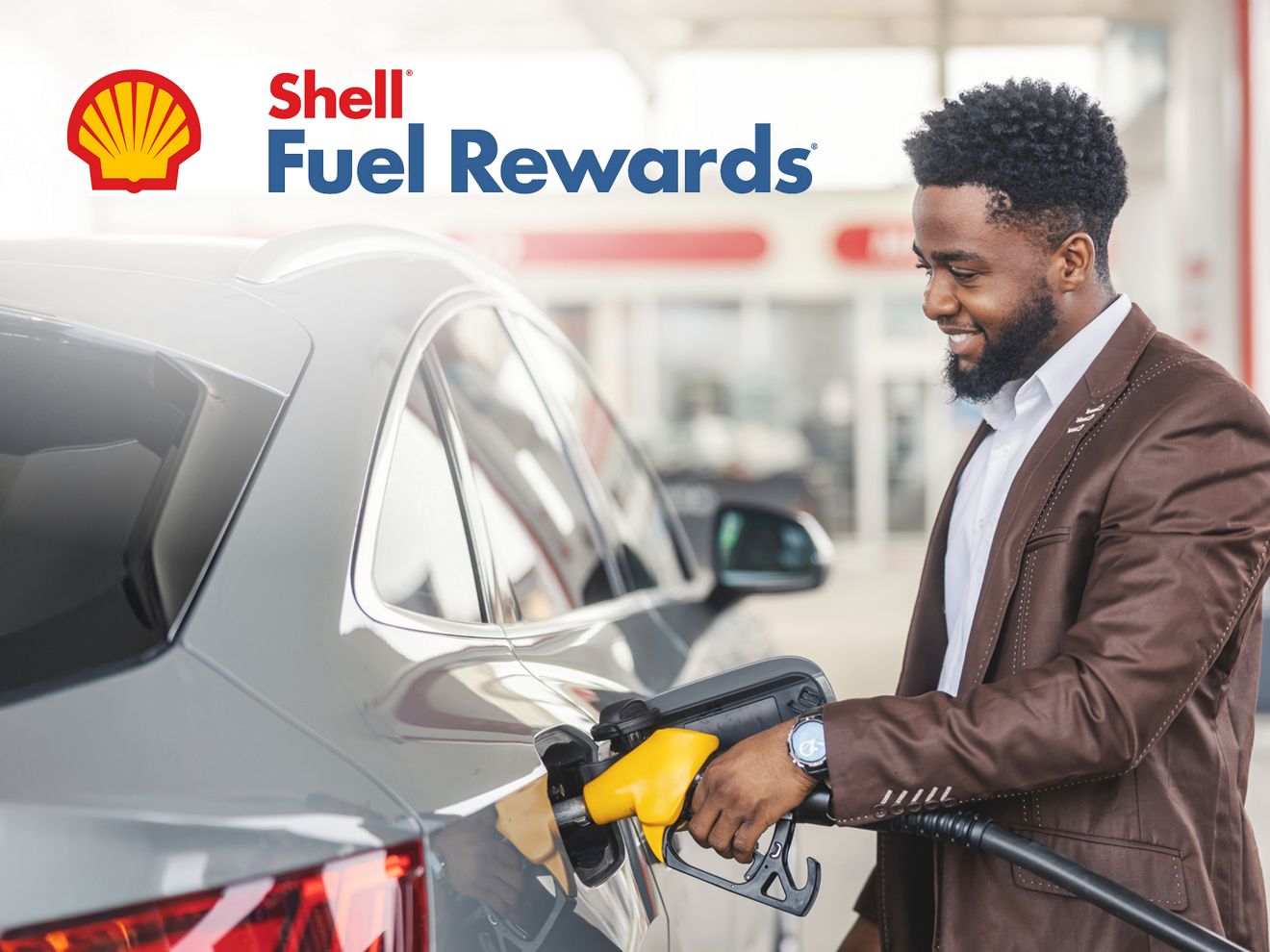 Una persona cargando combustible alegremente en una estación Shell. Hay un logotipo de Shell Fuel Rewards en la esquina superior izquierda.