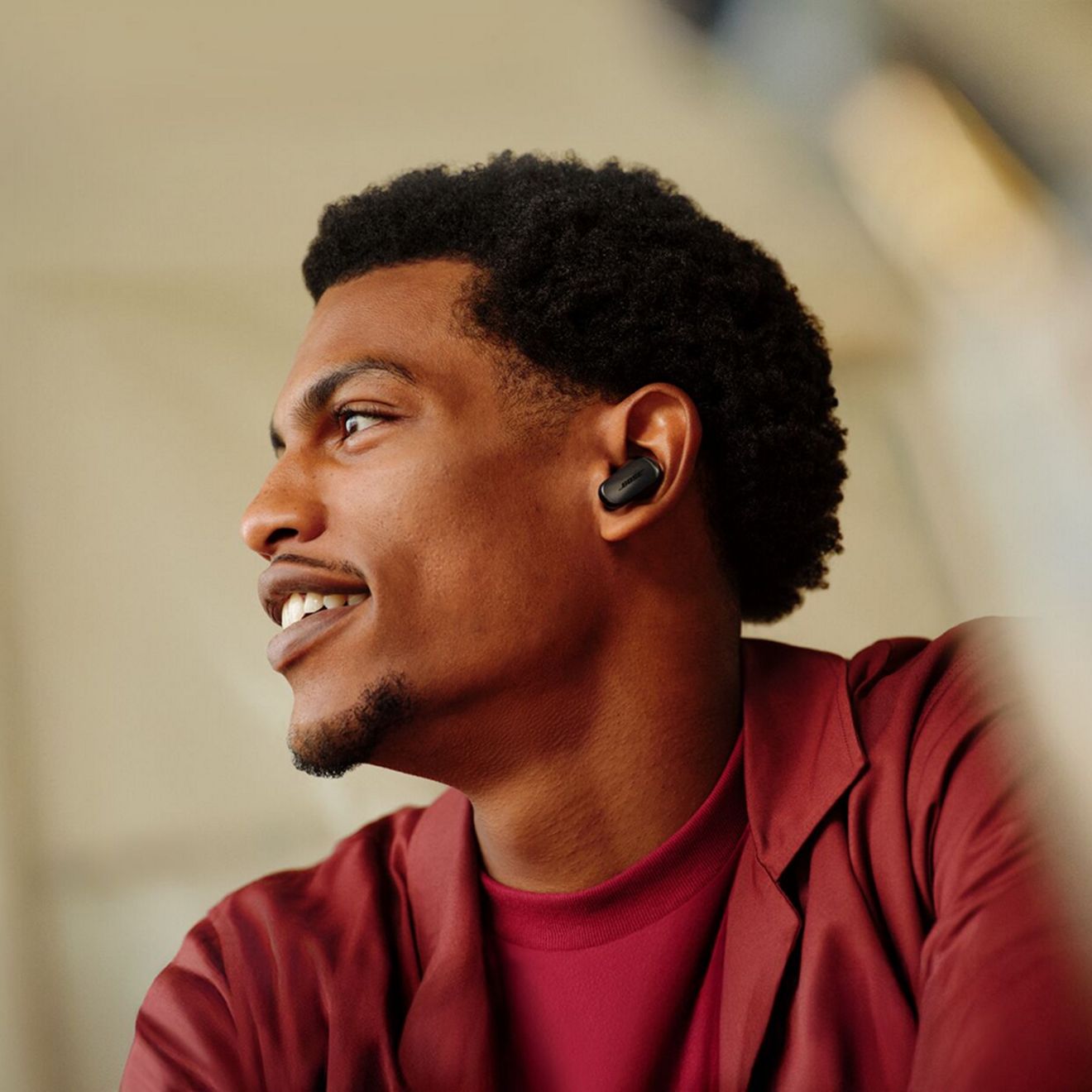 A man in a red shirt enjoys listening with his Bose Quiet Comfort Ultra Earbuds 2nd generation.