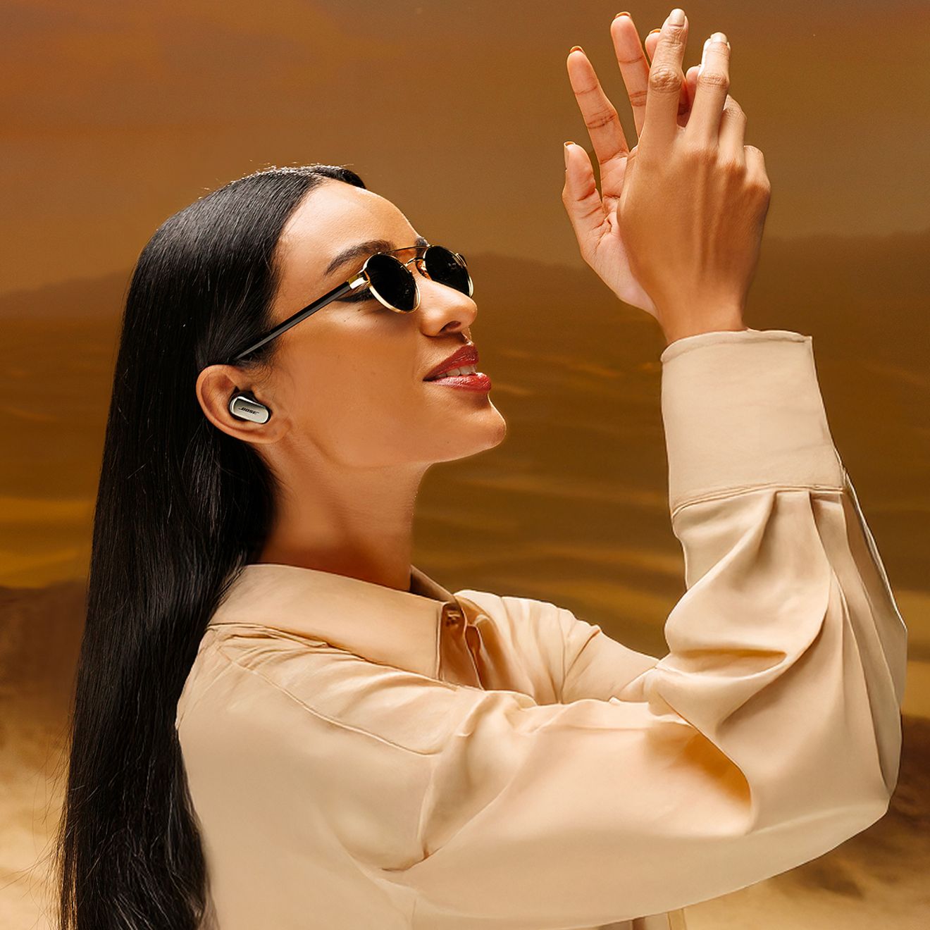 A woman is outside wearing sunglasses enjoying her Bose Quiet Comfort Ultra Earbuds 2nd generation.