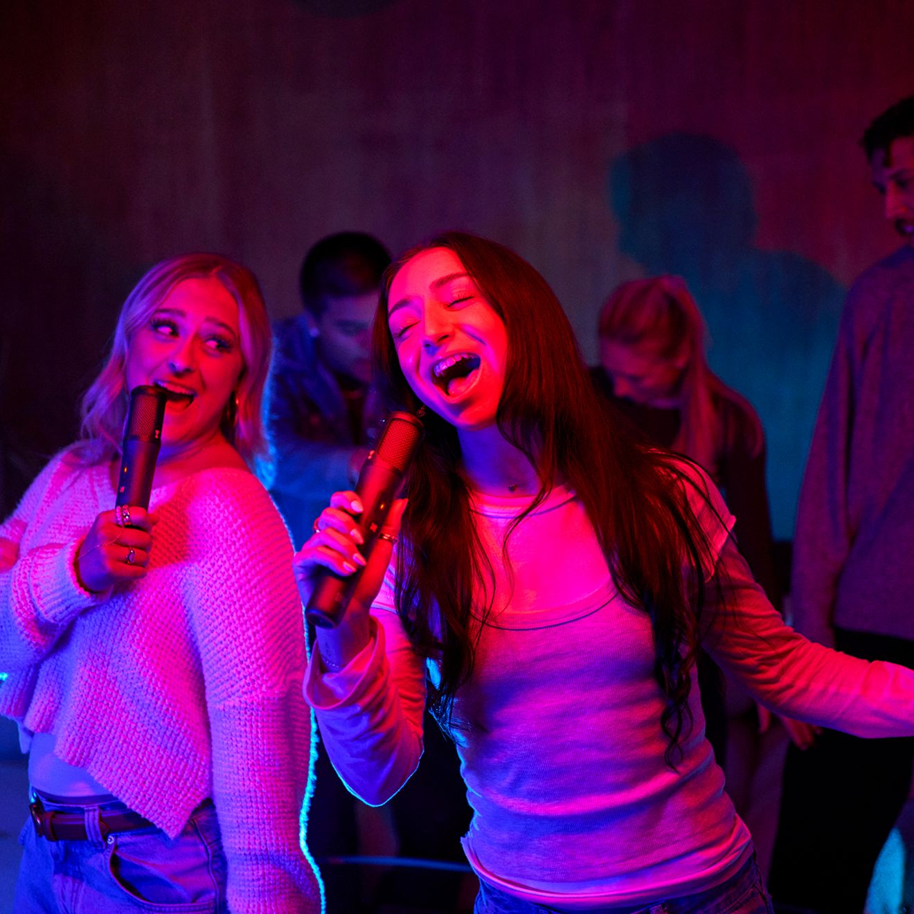 Two women are singing together using the JBL Easy Sing Mics 2.