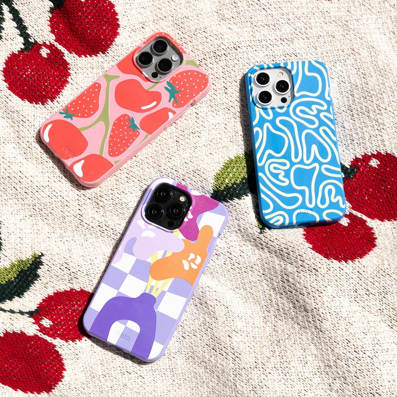 A group of three iPhone Pela phone cases are laid out on a blanket.