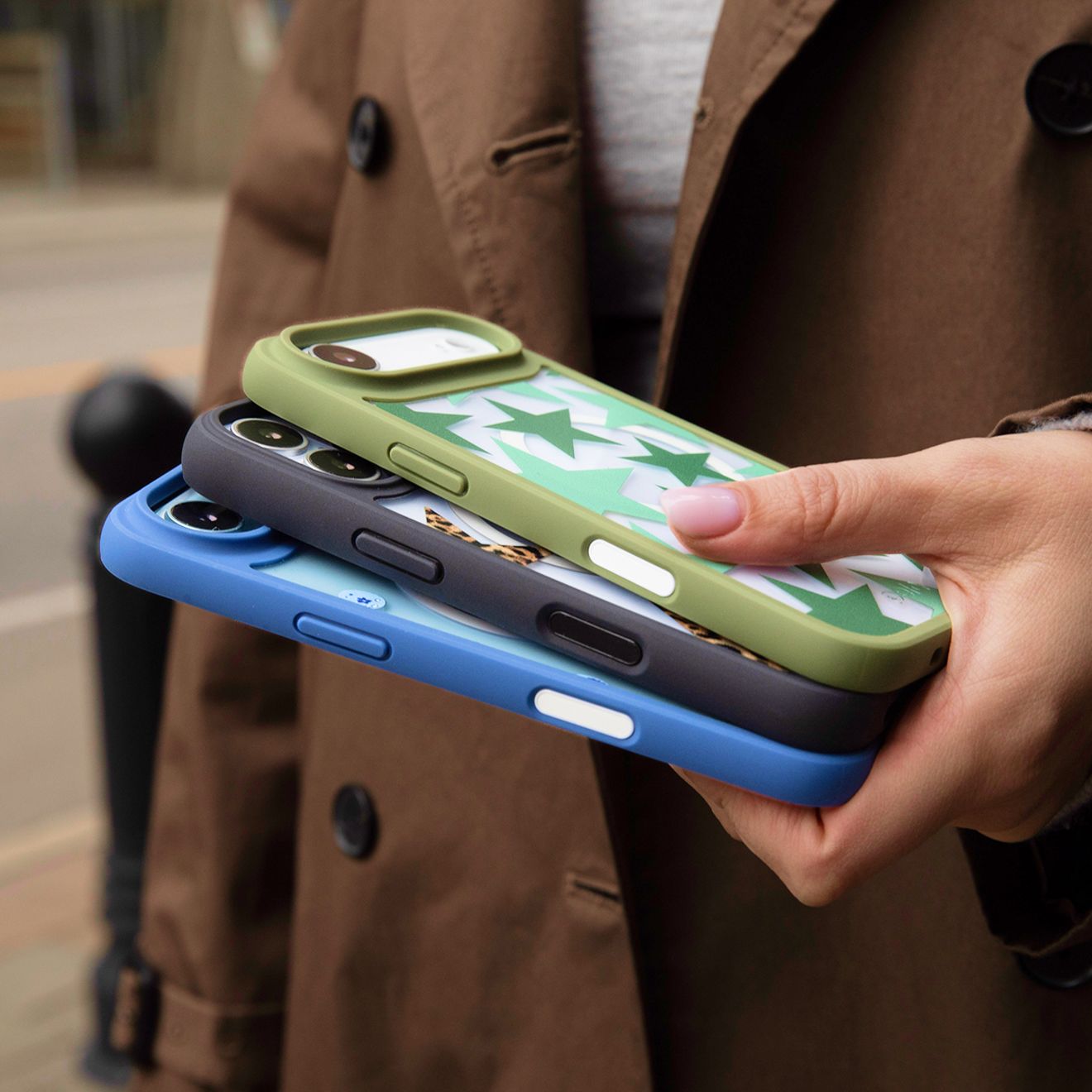 A man holds onto three iPhone Pela phone cases in one hand.