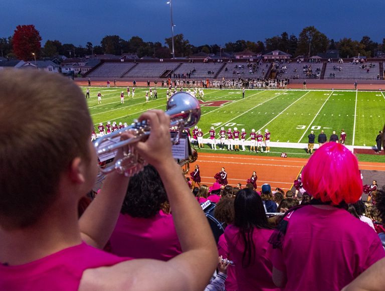 A high school band playing for their football team before a game.