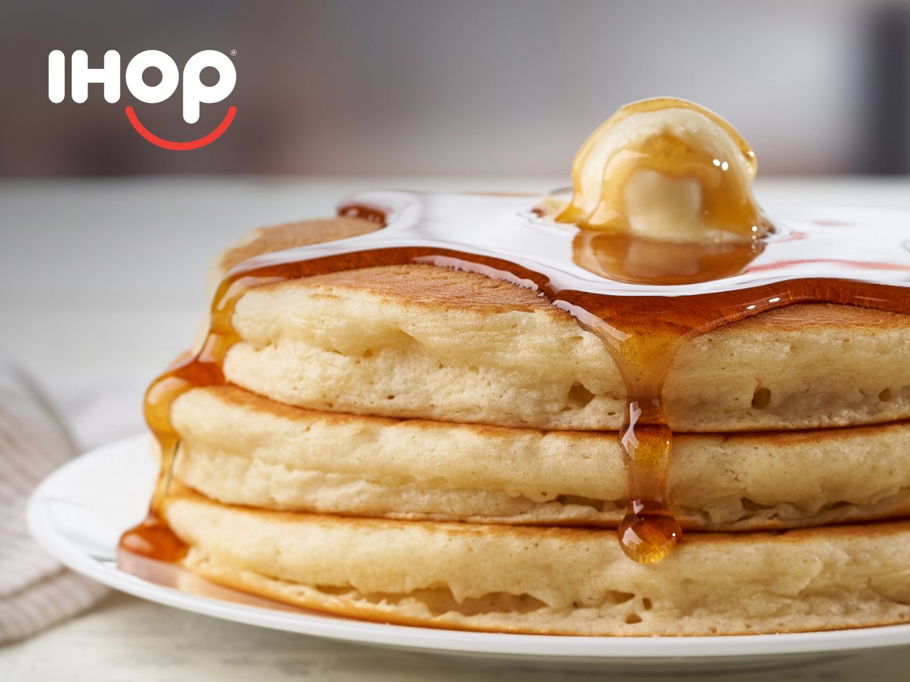 3 panqueques de IHOP, cubiertos de jarabe, apilados en un plato.