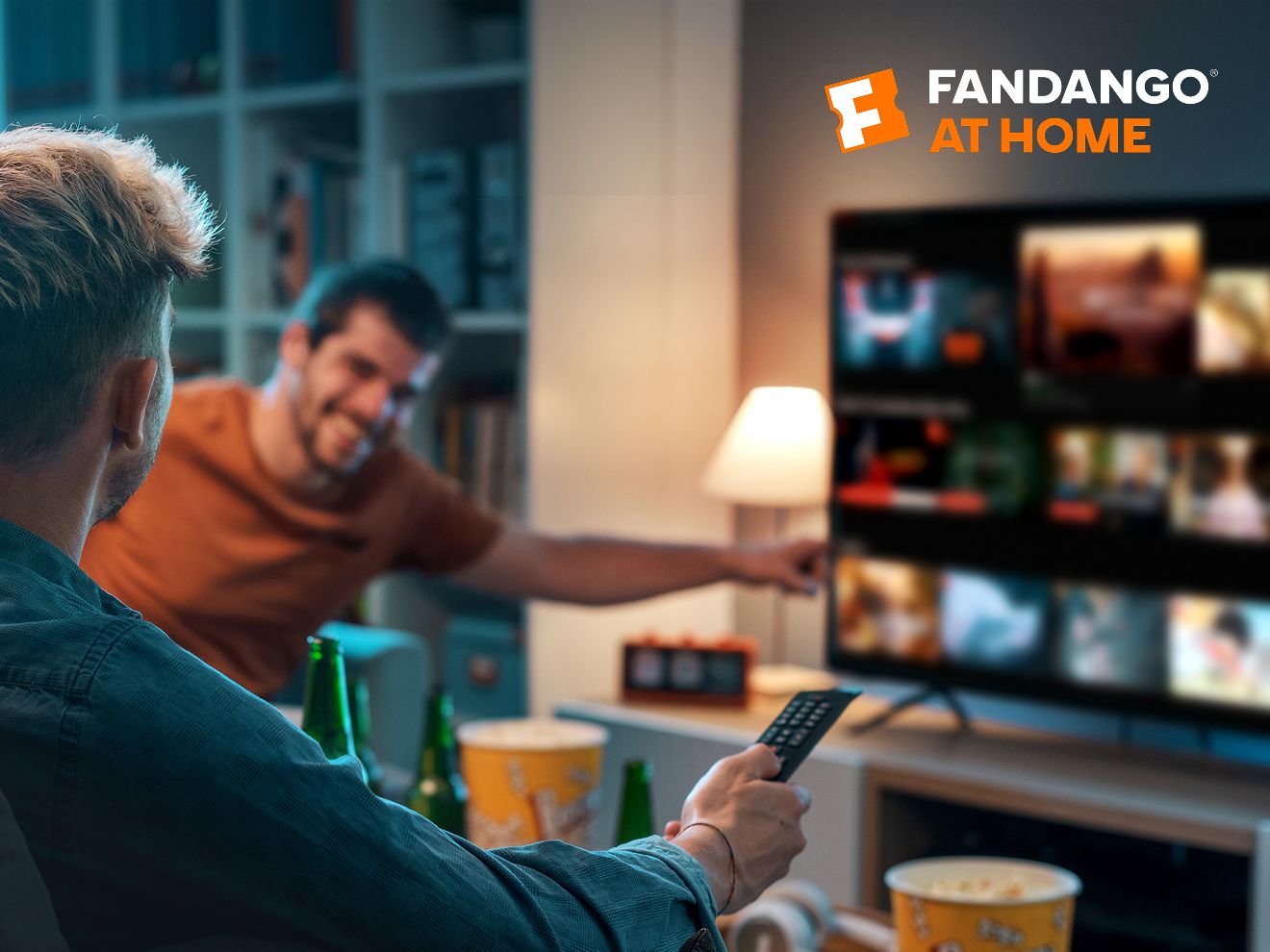 Two friends at home using their TV to select one film to watch with Fandango at Home.