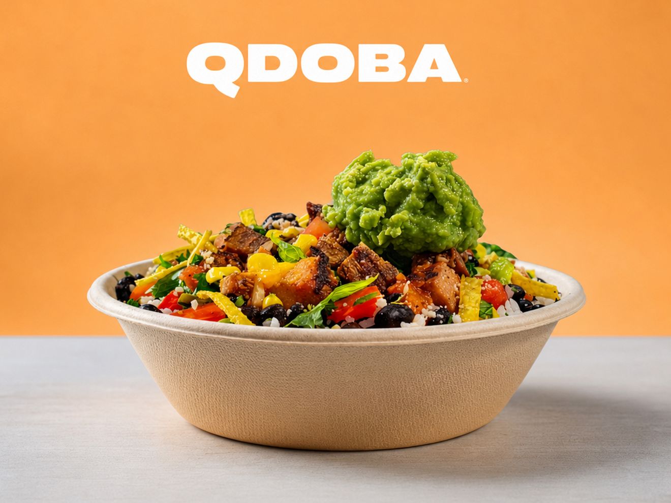 Plato principal de tamaño regular de QDOBA Mexican Eats con proteína a la parrilla, vegetales, frijoles, arroz y guacamole, servido en un bowl.