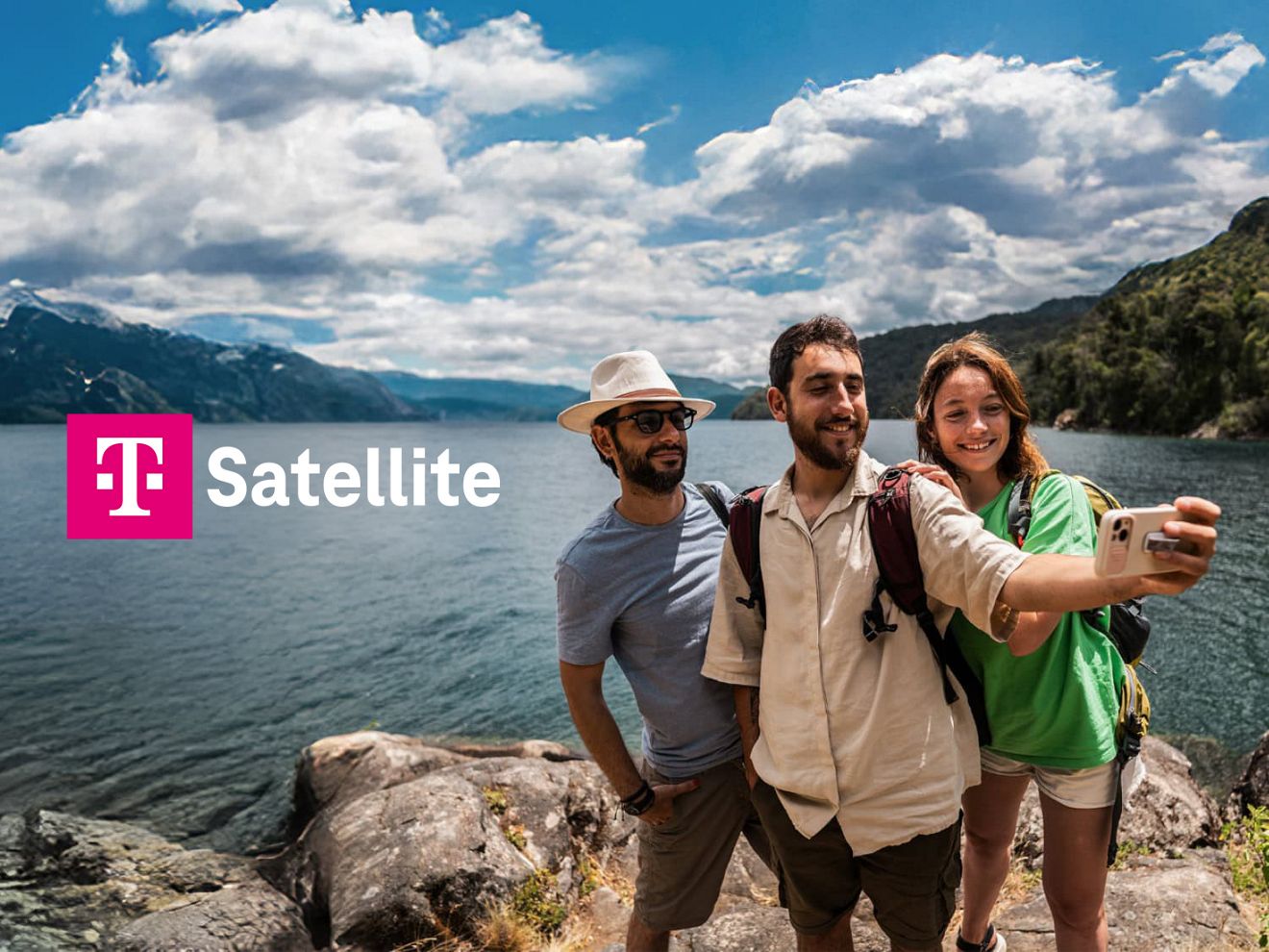 Group of friends taking a selfie on a rocky lakeshore with mountains in the background and “T Satellite with Starlink” text.