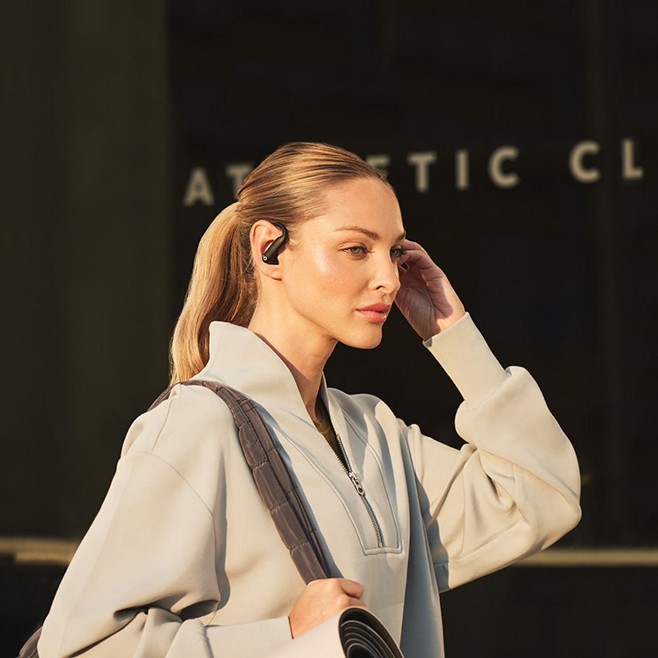 Woman adjusts headphones as she walks to work.