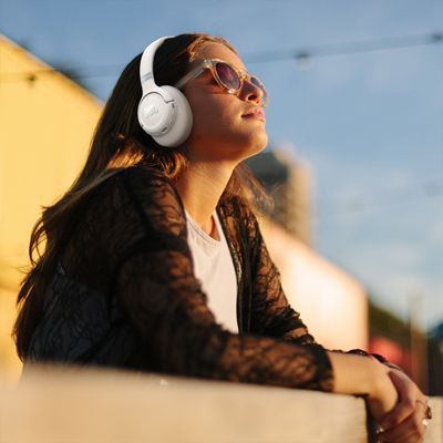 A woman listens to music with JBL 780NC headphones.