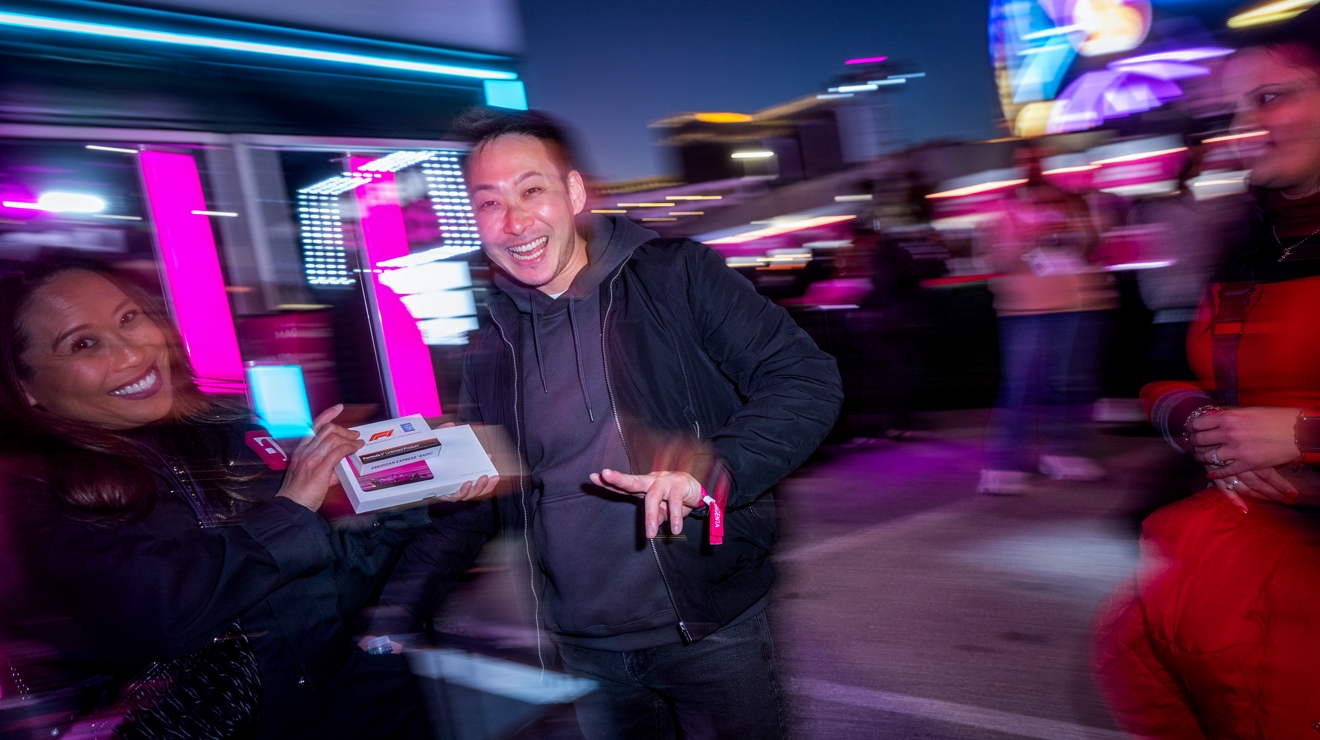 A man smiling while receiving a gift box from a Club Magenta staff member. 