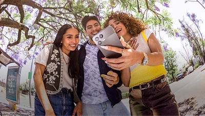 Three friends take a happy selfie under a tree.