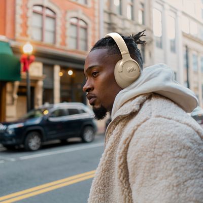 A man with JBL Tune 780NC headphones crosses a busy street.