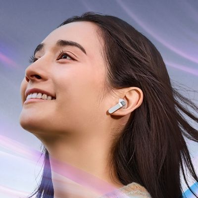 A woman surrounded by noise listens on her Samsung Galaxy Buds four earbuds.