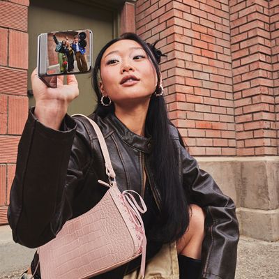 Motorola razr held upright outdoors, showing the outer display with camera preview on screen.