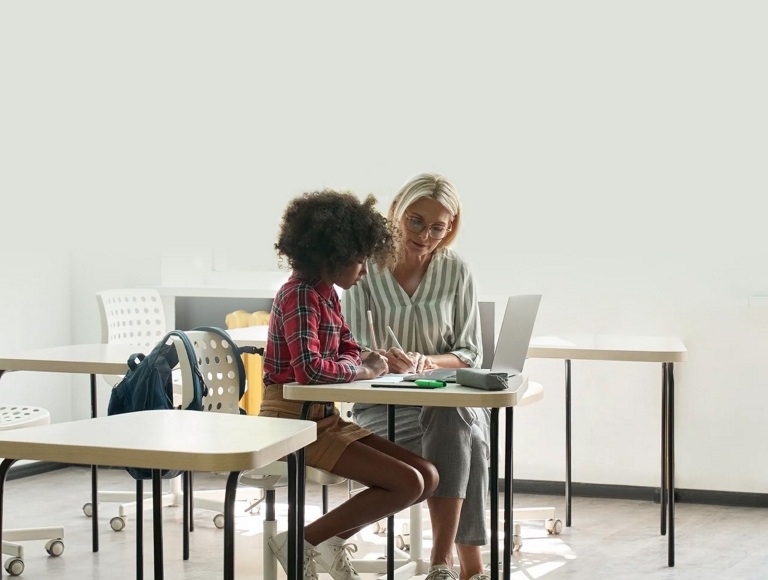 Teacher and student working together on a laptop in a classroom
