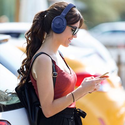 A woman with JBL Tune 780NC headphones looks at her phone.