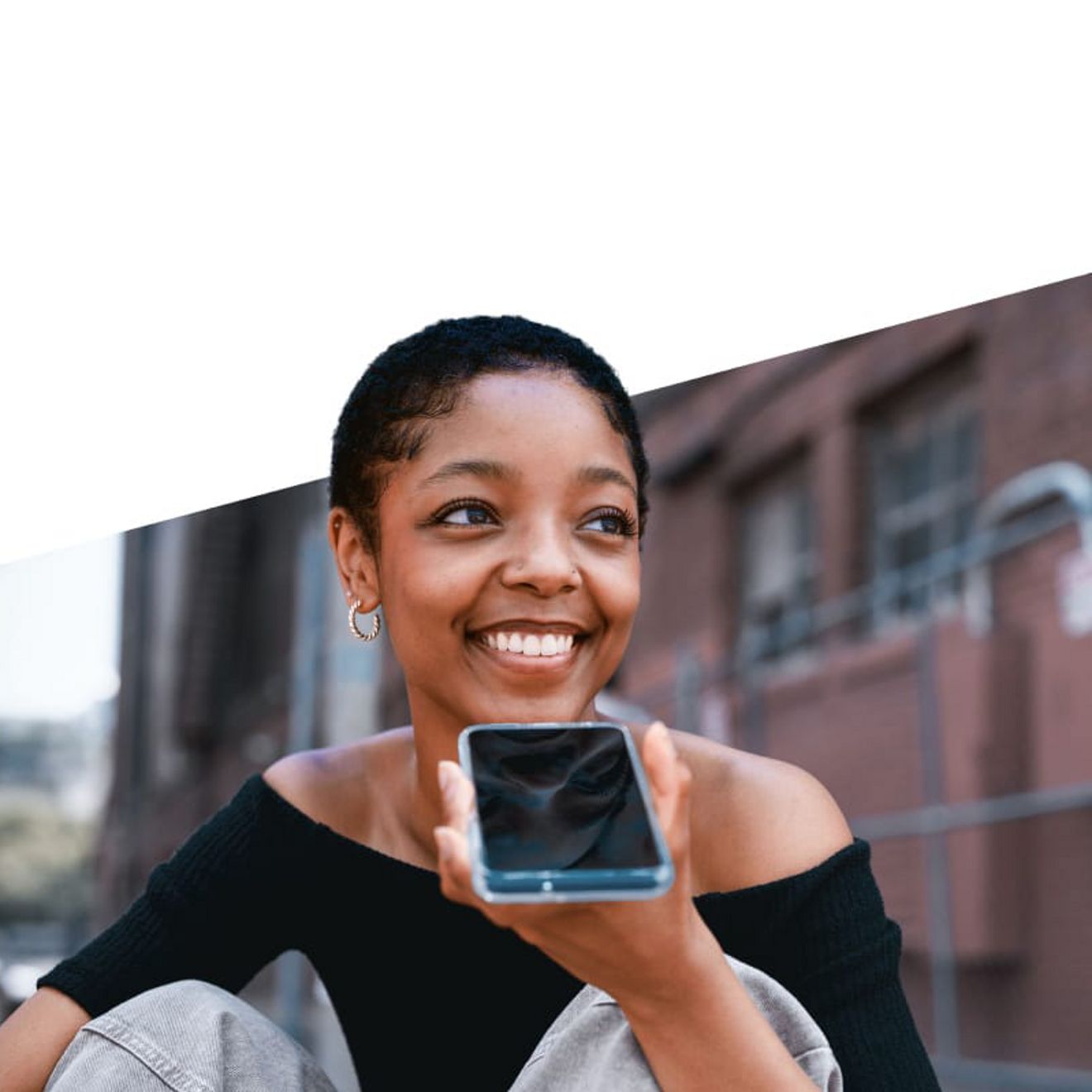person smiling and talking into their phone in speakerphone mode