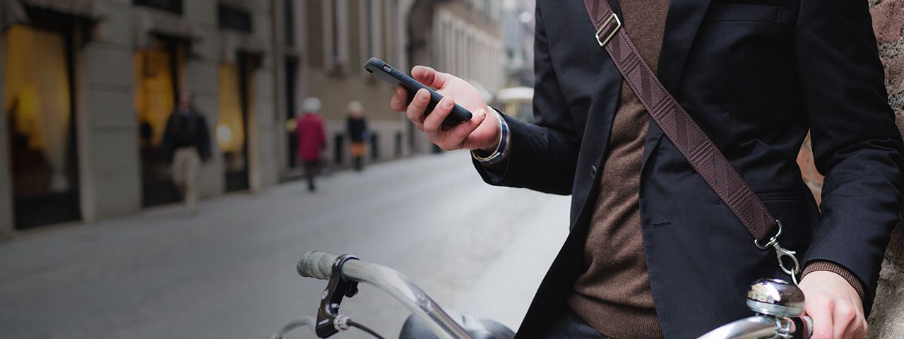A person holding a cell phone while on a bike.