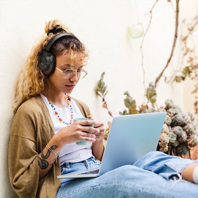 A woman looks at her laptop while wearing JBL Tune 780NC headphones.