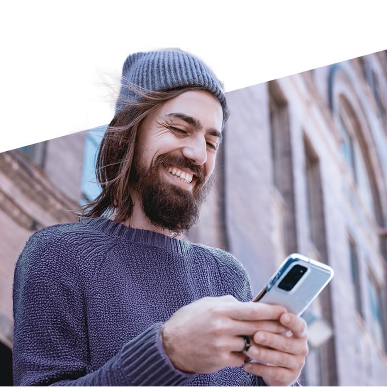 hombre con un gorro sonriendo a su teléfono