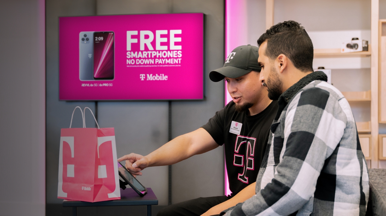 T-Mobile retail employee helping a customer in front of a digital screen.