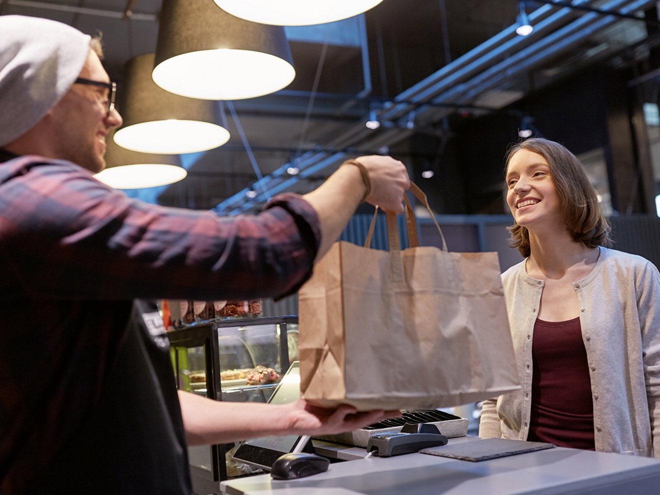 Employee handing shopping bag to smiling customer. 