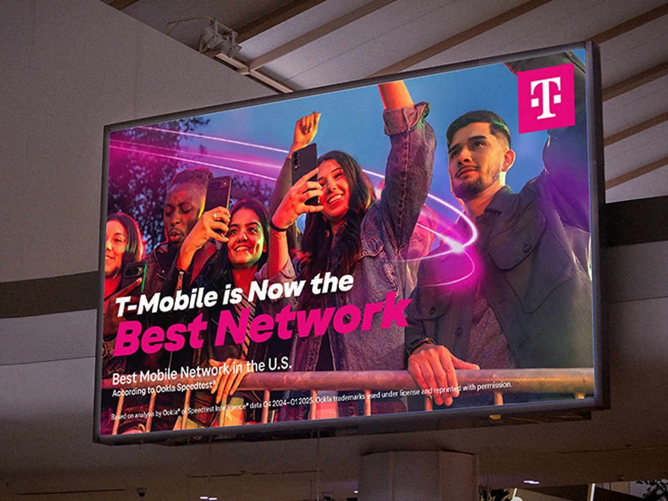 Large digital screen shows customers celebrating that T-Mobile is Now the Best Network. 