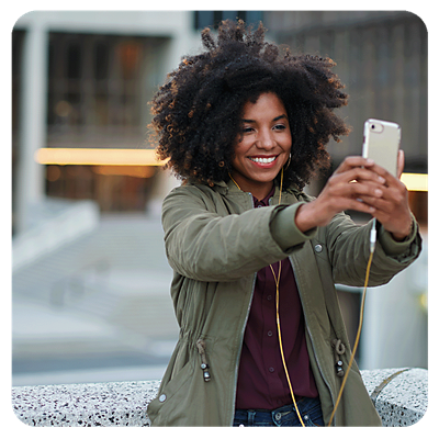 A woman holding up a phone and smiling.