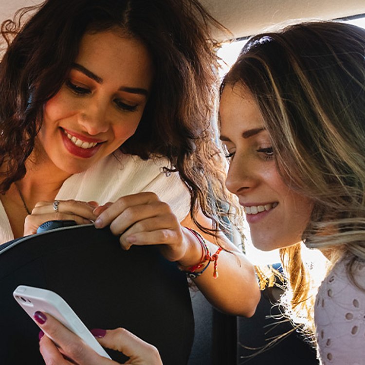 Two women in a car looking at a phone