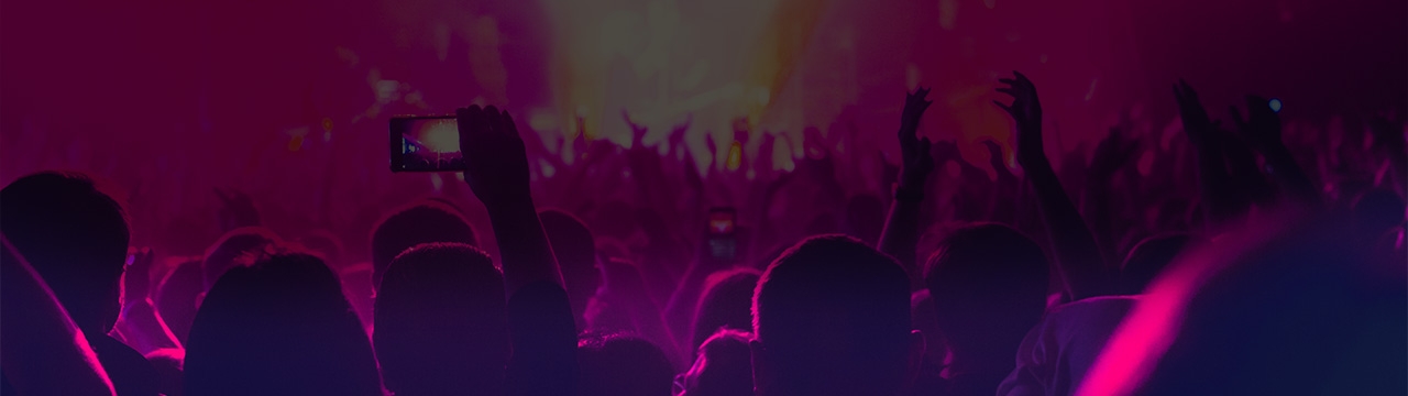 Fans in a concert crowd holding their phones up for photos