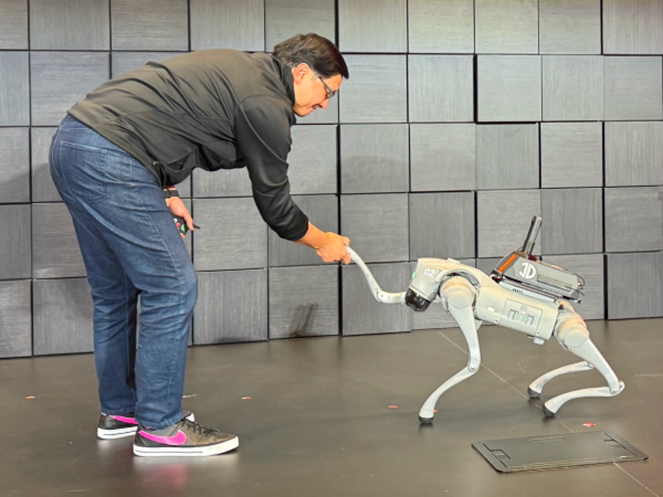 John is shaking hands with a four-legged robot.