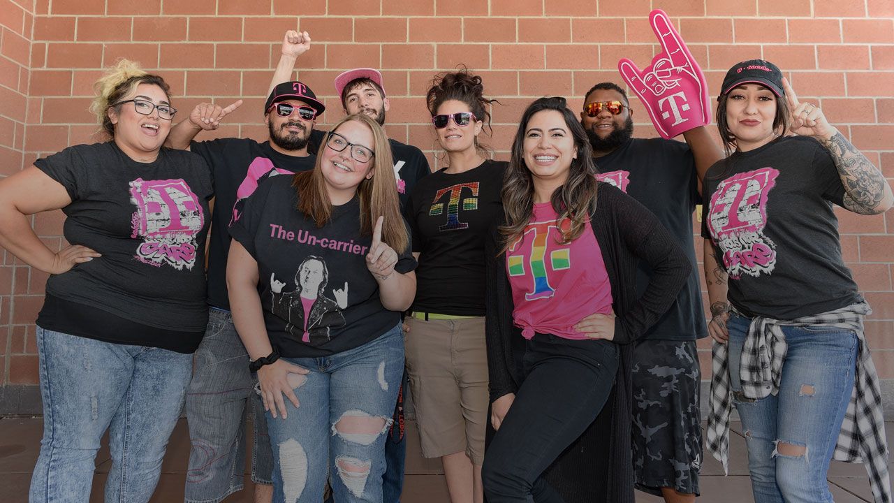 Men and women posing happily wearing T-Mobile t-shirts