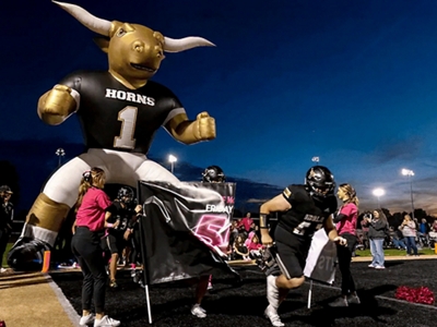 A giant inflatable Longhorn mascot is held up by several students.
