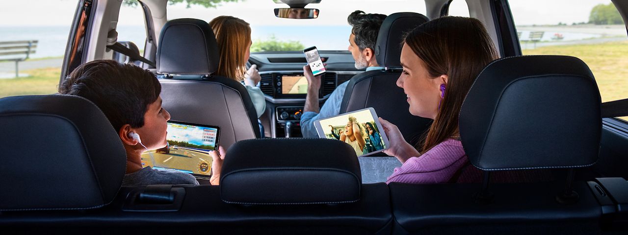 Family driving in car; each family member using individual Internet-connected devices.