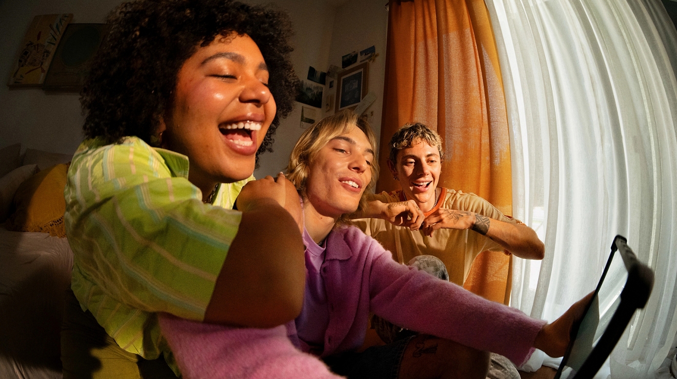 A group of 3 young people watching content on a tablet