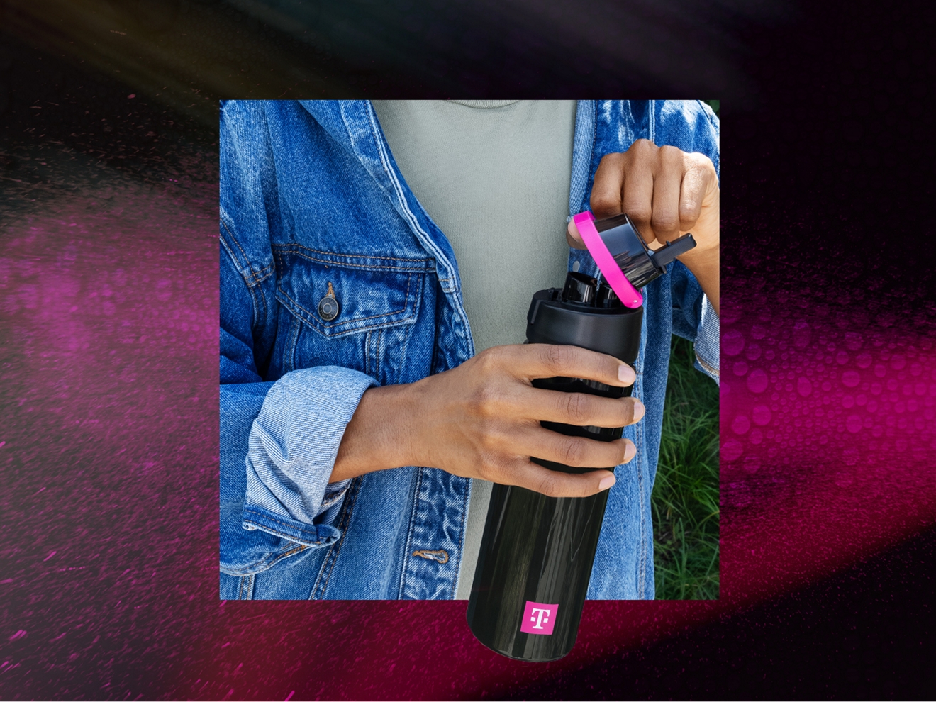 Closeup of person in denim jacket holding a black and magenta T-Mobile water bottle
