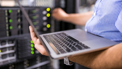 Una persona trabaja en su computadora y gira un dial en un servidor informático.