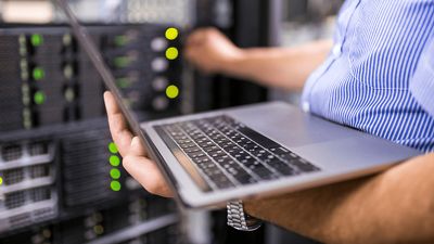 A person works on their computer and turns a dial on a computer server.