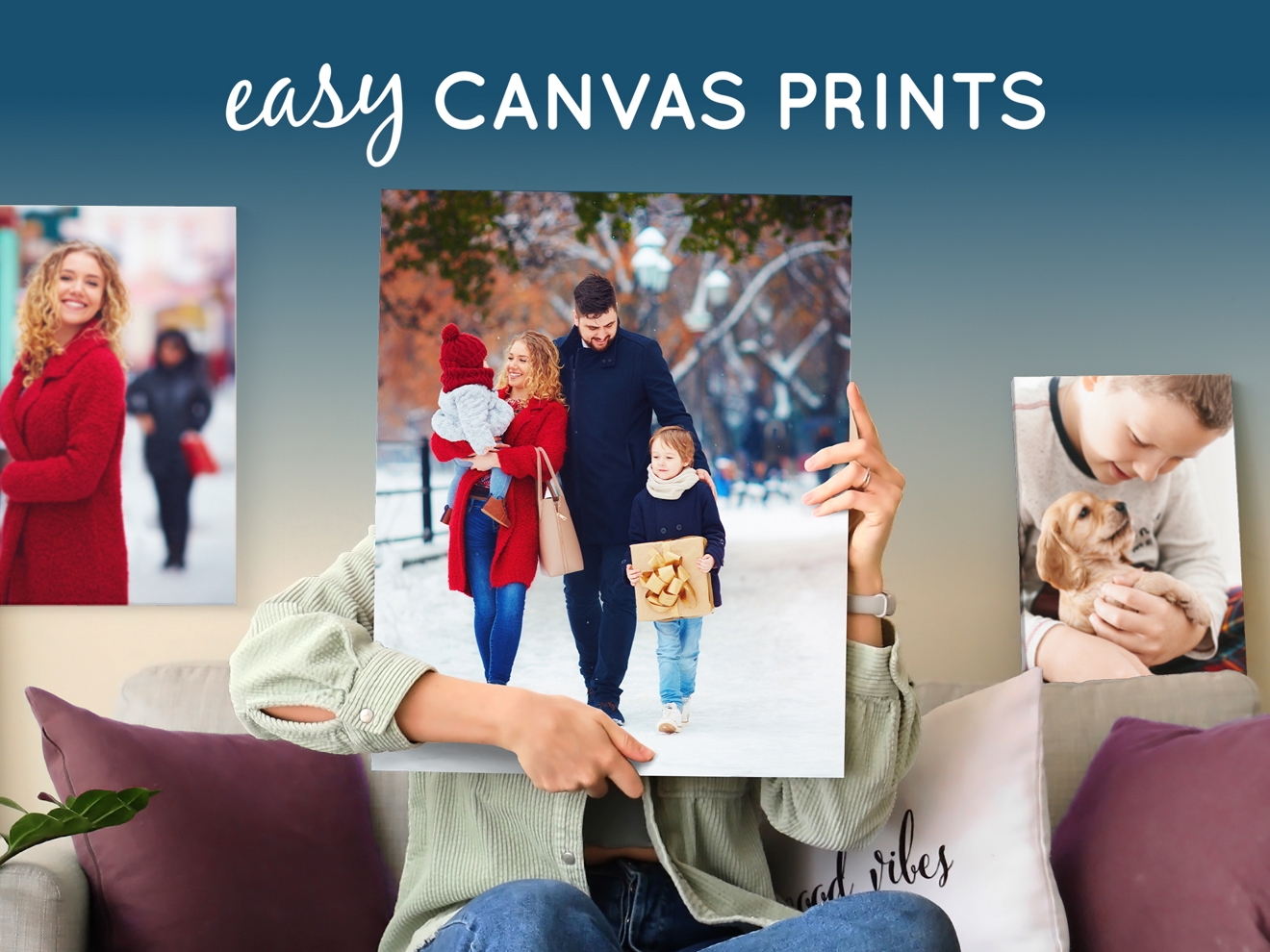 A person holds a canvas print of a family in the snow, with other photo prints in the background.