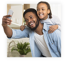 A smiling father and daughter pose for a mobile phone picture.