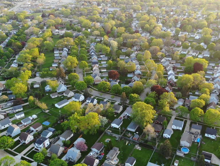 Aerial view of neighborhood with plenty of trees surrounding the houses. 