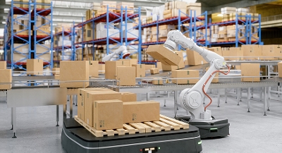 A piece of automated equipment moves boxes from a pallet to a conveyor in a warehouse.