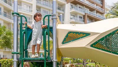 A child stands on a playground structure outside a hotel.
