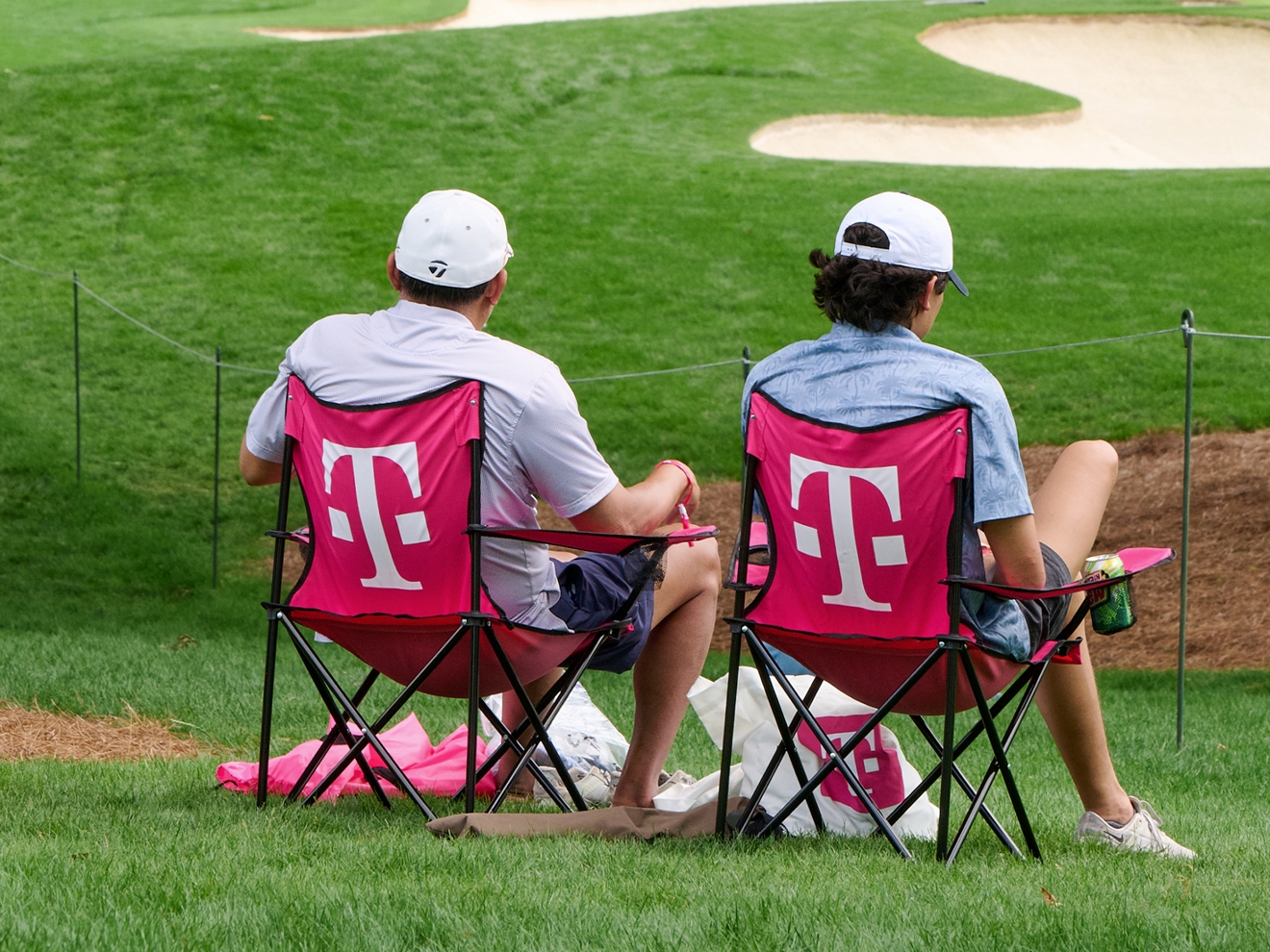 Two people sitting in T-Mobile branded lawn chairs. 