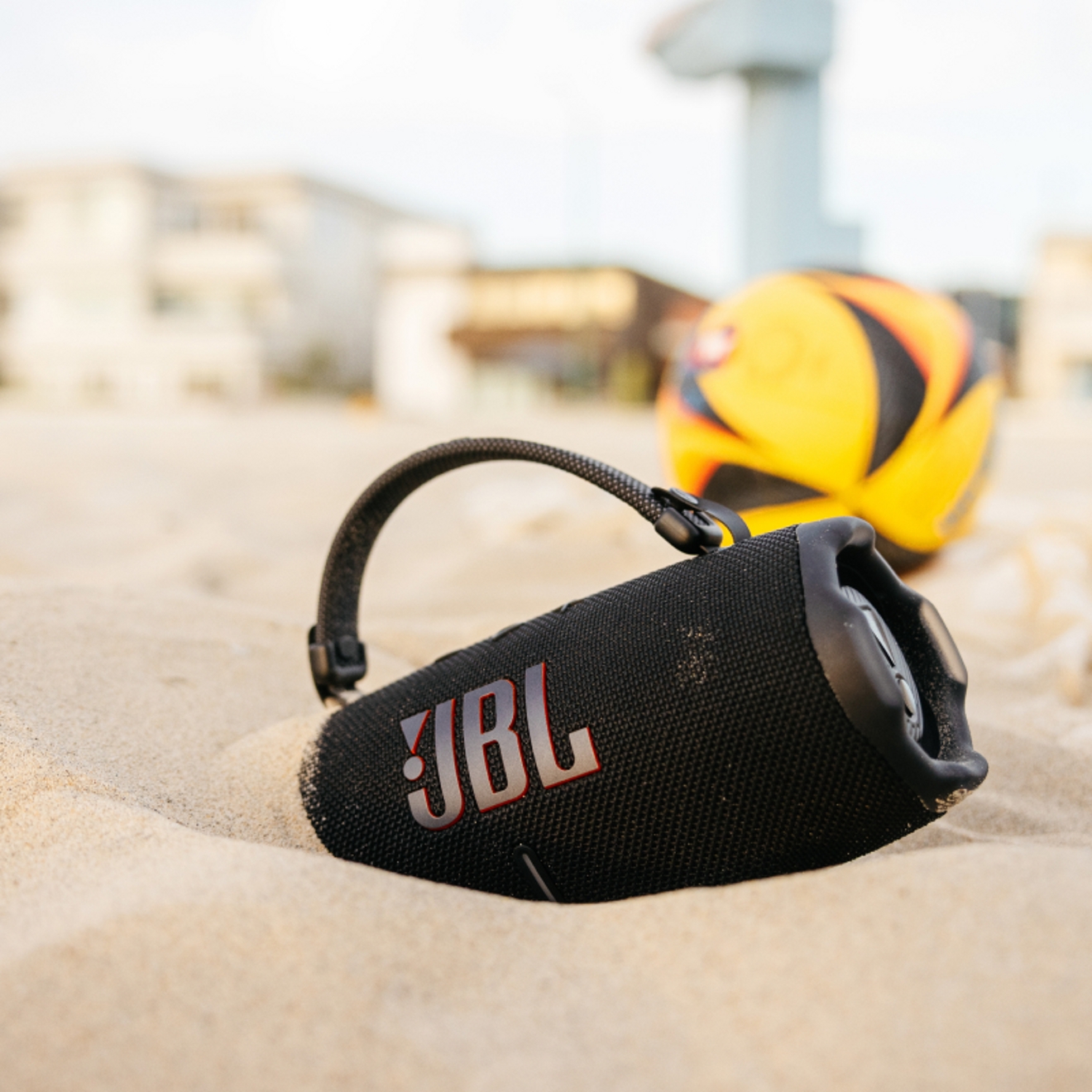 A JBL Charge device in the sand on a beach