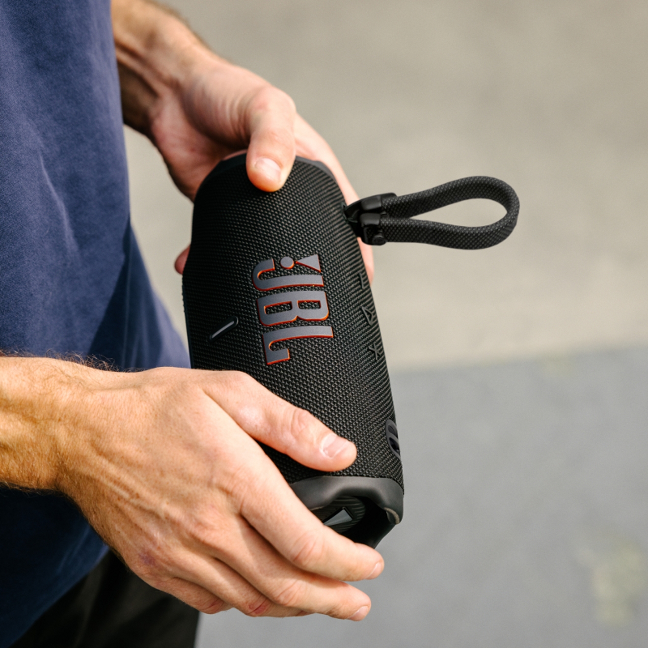 A man holding a JBL Charge device