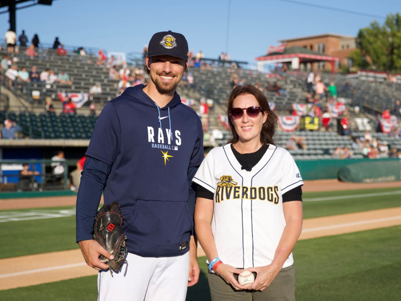 Julie Walker, a U.S. Air Force veteran, stands on a baseball field with a baseball player.
